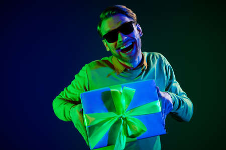 Photo of young fancy guy hold present wear spectacles sweater isolated on dark blue color backgroundの写真素材