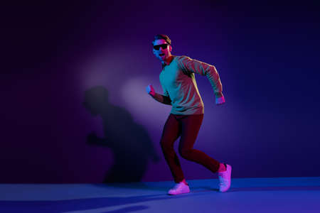 Full body photo of funky happy young positive man good mood dance isolated on neon light backgroundの写真素材