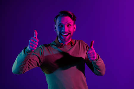 Photo portrait of man overjoyed smiling showing thumb-up gesture isolated on violet color backgroundの写真素材