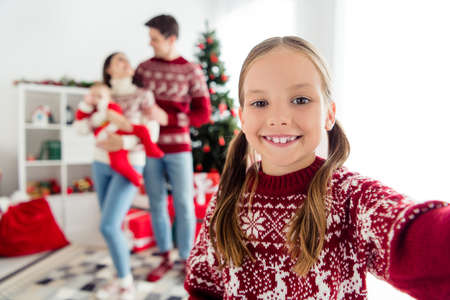 Photo of cheerful small girl take family portrait selfie eve wear sweater in decorated x-mas home indoorsの写真素材