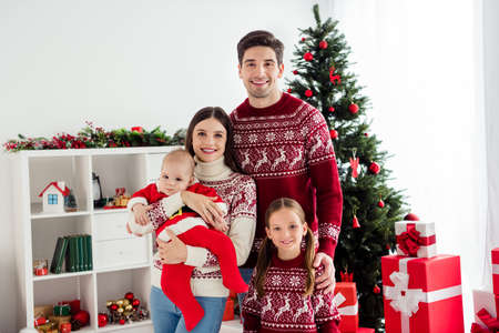 Photo of glad peaceful family cuddle infant small baby new year harmony wear sweater in decorated x-mas home indoorsの写真素材