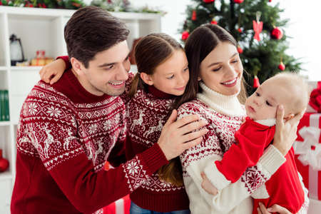 Photo of caring nice glad family embrace small baby child wear sweater in decorated x-mas home indoorsの写真素材