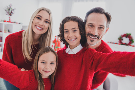 Self-portrait of careful beautiful handsome cheerful family mom dad schoolkids hugging spend eve advent at home house indoorsの写真素材