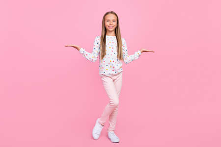 Photo of reliable promoter little lady palms presenting empty space wear dotted shirt isolated pink color backgroundの写真素材