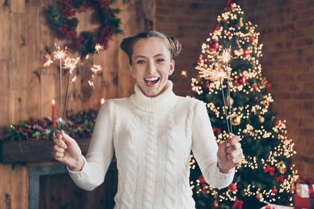 Photo of young cheerful excited girl celebration new year bengal lights decoration spirit winter indoorsの写真素材