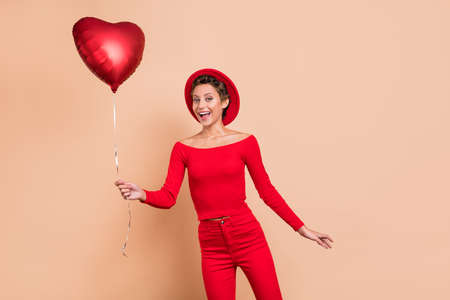 Photo of excited cheerful charming lady hold balloon wear glamour clothes isolated on pastel beige color backgroundの写真素材