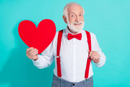 Portrait of attractive cheerful mister holding in hand heart amour feelings isolated over bright teal turquoise color backgroundの写真素材