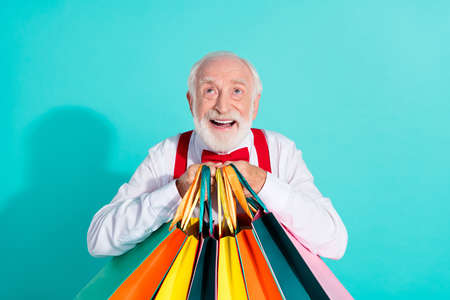 Portrait of attractive cheerful grey-haired man buying new things clothes looking up isolated on...