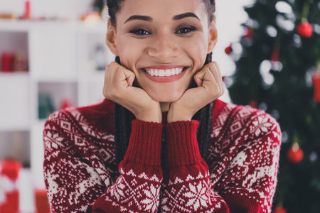 Cropped view portrait of attractive cheerful girl enjoying good mood festal time day wear ugly jumper at decorated home indoorsの写真素材