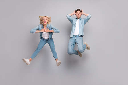Full length photo of impressed couple jump wear jeans shirt shoes isolated on grey color background