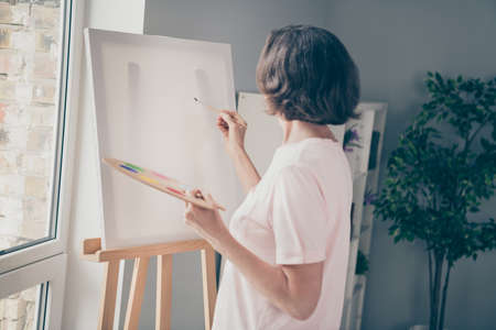 Photo of cute sweet old woman dressed casual outfit drawing picture holding palette brush indoors home roomの写真素材