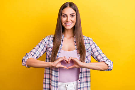 Photo of young woman happy positive smile show fingers heart symbol love isolated over yellow color...