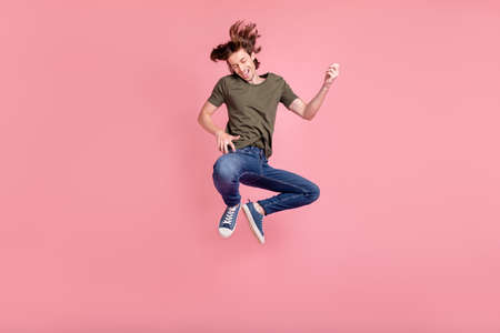 Full length photo of young guy happy positive smile jump play guitar music isolated over pastel...