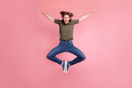 Full body photo of young man good mood fly arms balance jumper wings isolated over pink color...