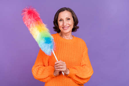 Photo of cheerful aged woman cleaning chores maid equipment disinfection isolated over purple color...