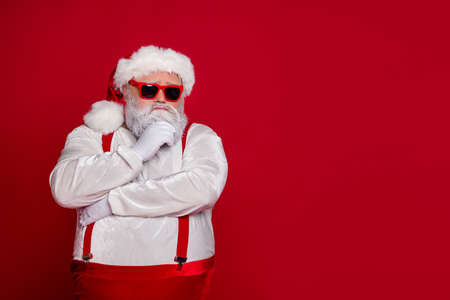 Photo of minded old man ponder december preparation finger chin wear santa hat costume isolated red color backgroundの写真素材