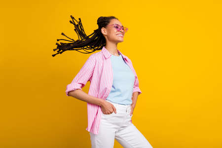 Photo of young happy dreamy afro american woman look empty space wear sunglass isolated on yellow...