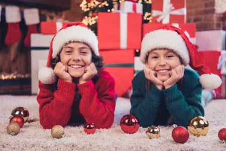 Portrait of attractive cheerful friends siblings lying on floor having fun newyear atmosphere tradition at decorated home indoorsの写真素材