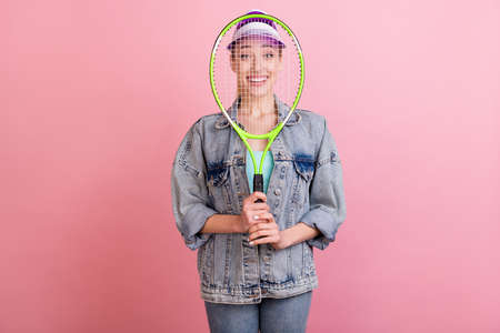 Portrait of attractive cheerful girl higing face behind racket fooling isolated over pink pastel color backgroundの写真素材