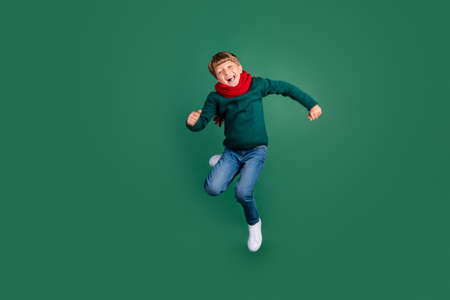 Photo of sweet pretty schoolboy dressed green sweater jumping high smiling isolated green color backgroundの写真素材