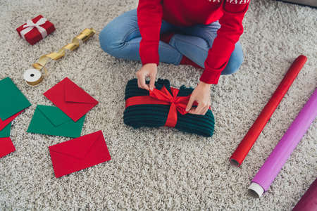 Cropped photo of lady hands prepare knitwear gift pack red bow wear hat sweater in decorated x-mas home indoorsの写真素材