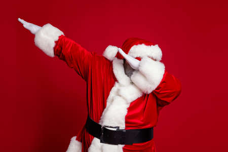 Photo of funky positive carefree old man dance make dab move wear santa hat costume isolated red...