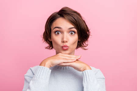 Photo of charming brunette haired young woman hold hand face good mood send air kiss isolated on...
