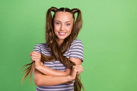 Photo of positive cool happy young lady hand hair cross salon treatment hairdo isolated on green color backgroundの写真素材