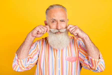 Photo of funny suspicious age gentleman wear striped shirt arms mustaches isolated yellow color...
