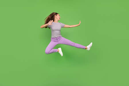 Full size photo of positive happy young woman jump up look empty space fighter isolated on green...