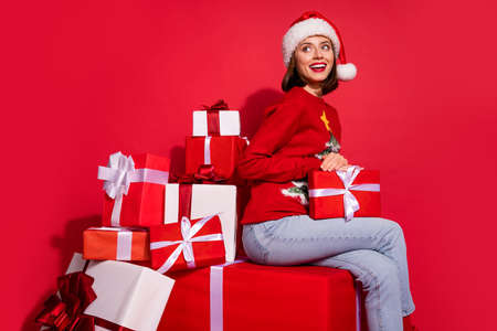 Photo of shiny dreamy woman wear ornament sweater sitting holding new year gifts looking empty space isolated red color backgroundの写真素材