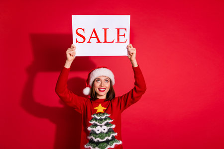 Photo of shiny dreamy young woman wear ornament sweater rising christmas sale poster isolated red...