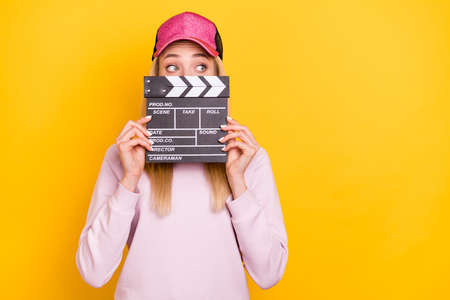 Photo of young girl close cover mouth clapperboard scene film maker cinematography isolated over yellow color backgroundの写真素材