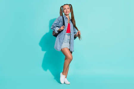 Photo of funny dreamy young lady wear jeans shirt rucksack smiling looking empty space isolated...