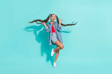 Photo of shocked attractive young woman dressed denim jacket looking empty space rising arms smiling...