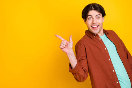 Photo of sweet charming young guy dressed brown shirt glasses drinking pointing finger empty space...