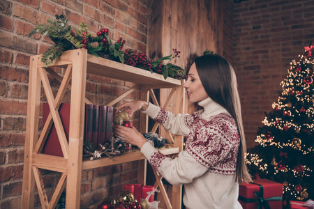 Profile photo of lovely mature lady hang ball on tree wear pullover christmas indoors at homeの写真素材