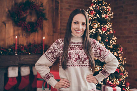 Portrait of lovely cheerful woman in ugly jumper hands on hips spending time event at decorated...