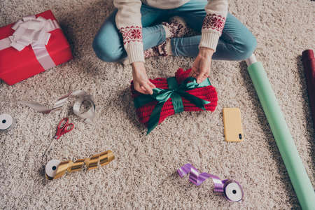 Cropped view of woman making gift package preparing festal day time event occasion workshop at home cozy soft carpet indoorsの写真素材