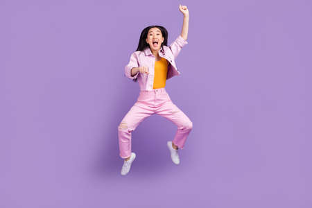 Full body photo of hooray millennial brunette lady jump wear jacket jeans sneakers isolated on violet backgroundの写真素材