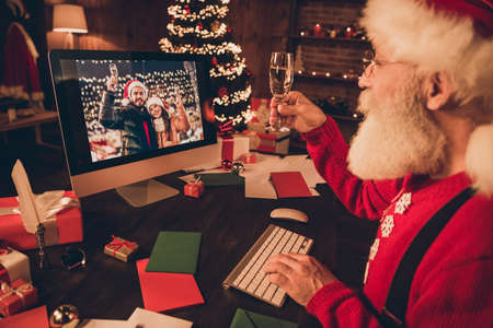 Photo of cute funny mature man dressed santa costume speaking modern gadget rising wine glass...