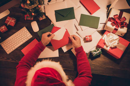 Top above photo of incognito santa claus sit workspace open envelop letter wear hat sweater in north...