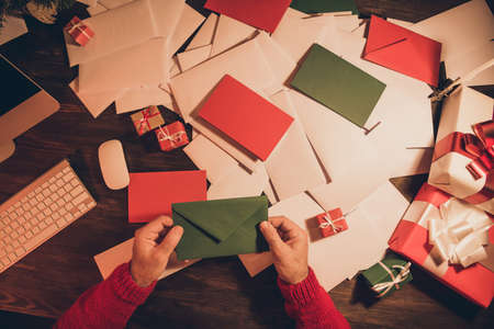 Top view photo hands keeping green letter wishlist before christmas holidays in winter