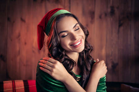 Portrait of attractive cheerful wavy-haired dreamy calm girl elf hugging herself eve at home modern...