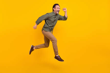Full length body size view of attractive cheerful man employee jumping running isolated over bright yellow color backgroundの写真素材