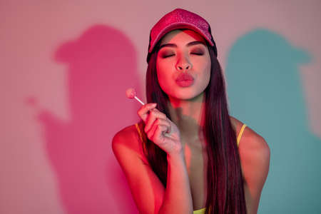 Portrait of attractive dreamy alluring girl eating lollipop sending air kiss isolated over shine purple violet color backgroundの写真素材