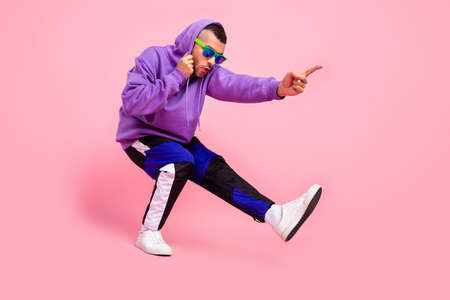 Full body profile side photo of young funky guy fooling indicate finger empty space isolated over pink color backgroundの写真素材