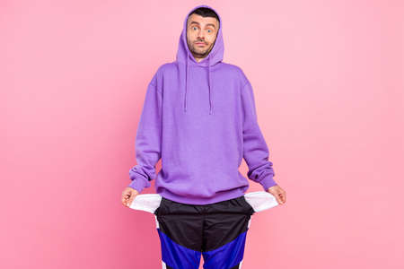 Photo of impressed millennial brunet guy wear violet hoodie isolated on pink color backgroundの写真素材