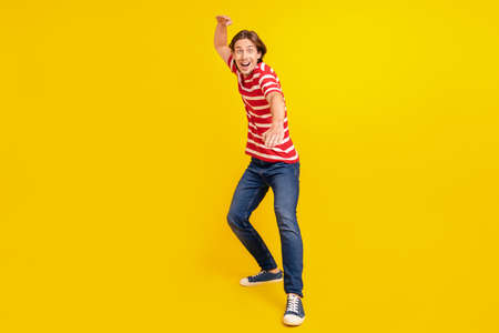 Full length body size view of attractive cheerful crazy guy dancing fooling isolated over bright yellow color backgroundの写真素材