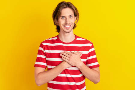 Photo of funny charming young man wear striped t-shirt arms chest smiling isolated yellow color backgroundの写真素材